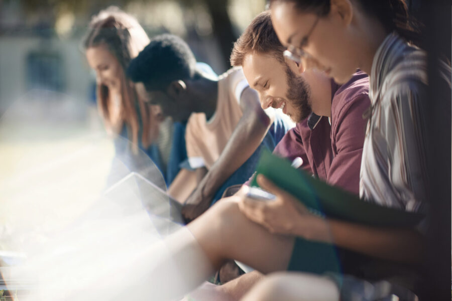 Multicultural students sit together in the park and study, exchange ideas and work on a project.