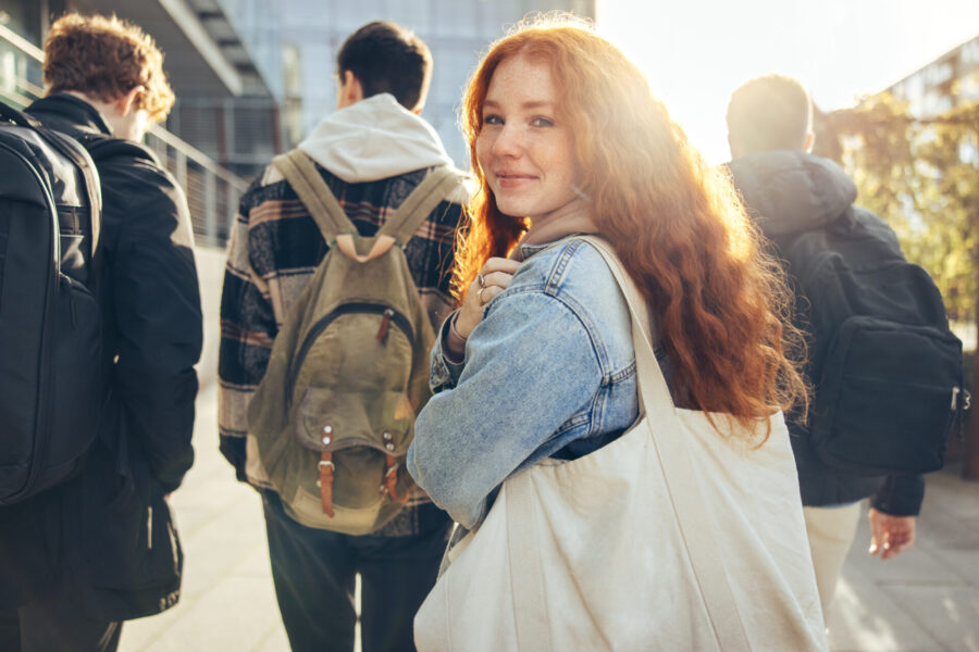 A group of students on their way to a lecture. A student turns to the camera with a smile.