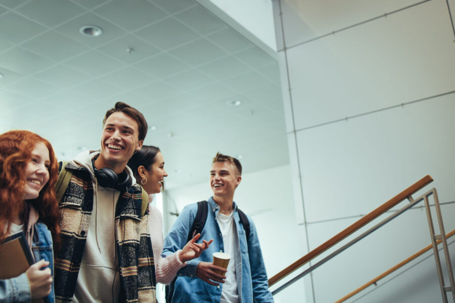 A group of young people walk through a large, modern building, laughing and chatting.