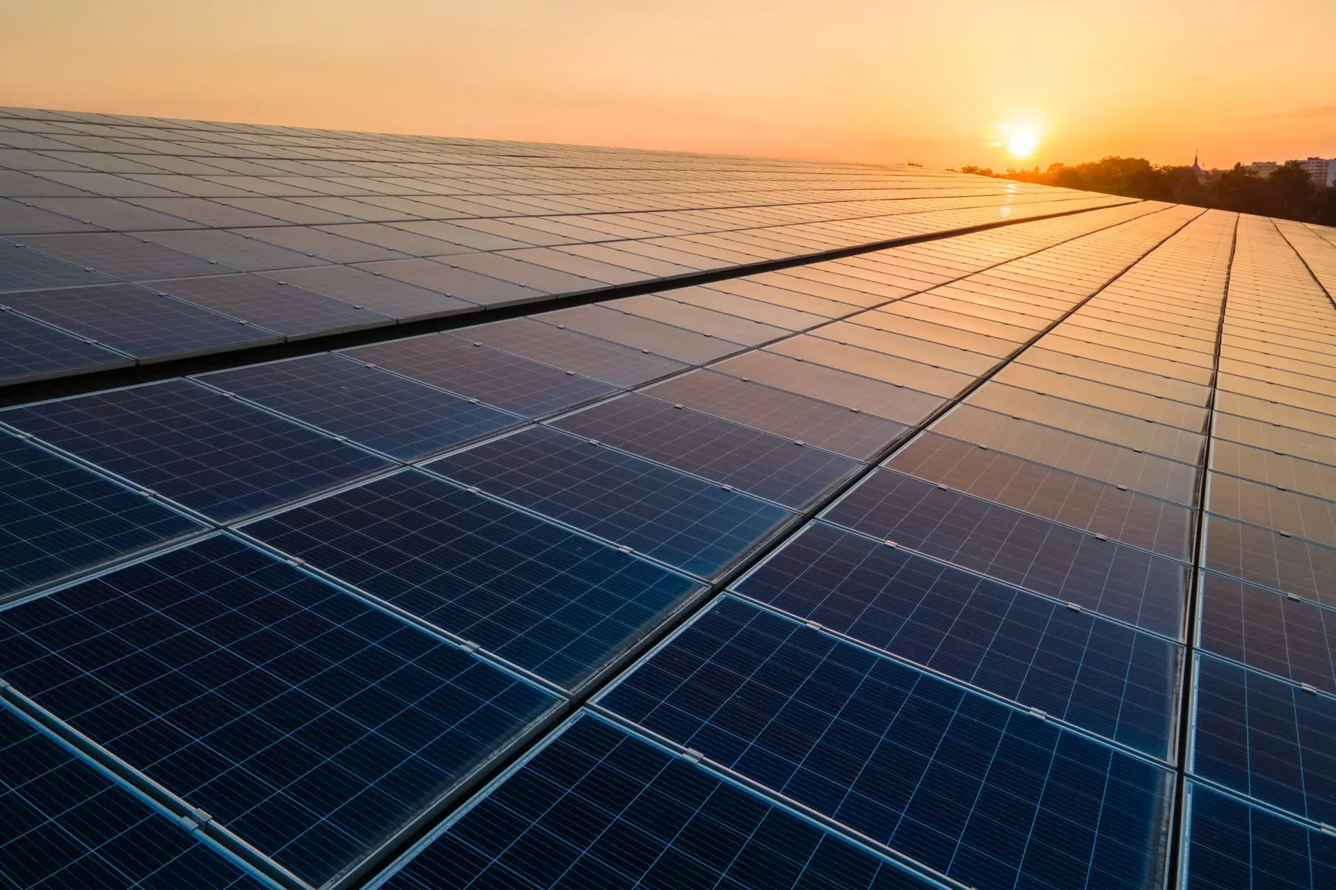 Blaue Photovoltaik-Solarzellen auf einem Dach bei Sonnenuntergang, die sauberen Ökostrom erzeugen.