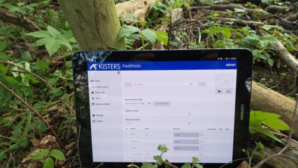 Auf einem Baumstamm im Wald befindet sich ein Tablet-Computer.