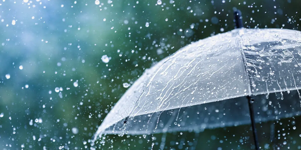 Transparent umbrella with water drops during heavy rain.