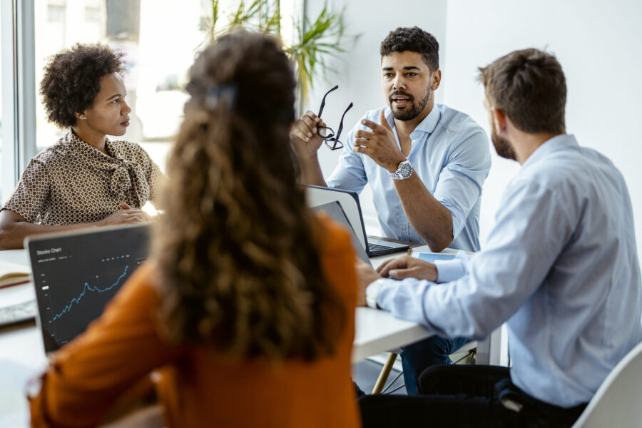 Business conversation between several people, a man gesticulating and explaining something with glasses in his hand.