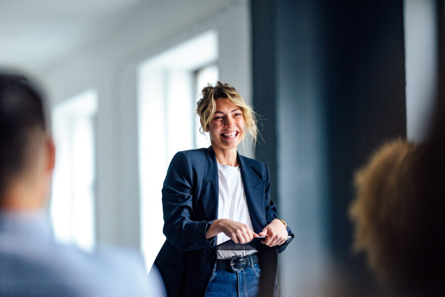 Young businesswoman gives an inspiring presentation and smiles in front of her audience in a modern office.
