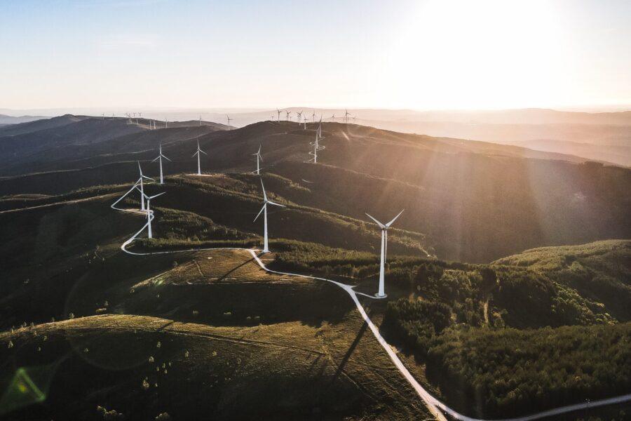 Wind turbines in a hilly mountain landscape under a bright sun - sustainable energy generation in nature.