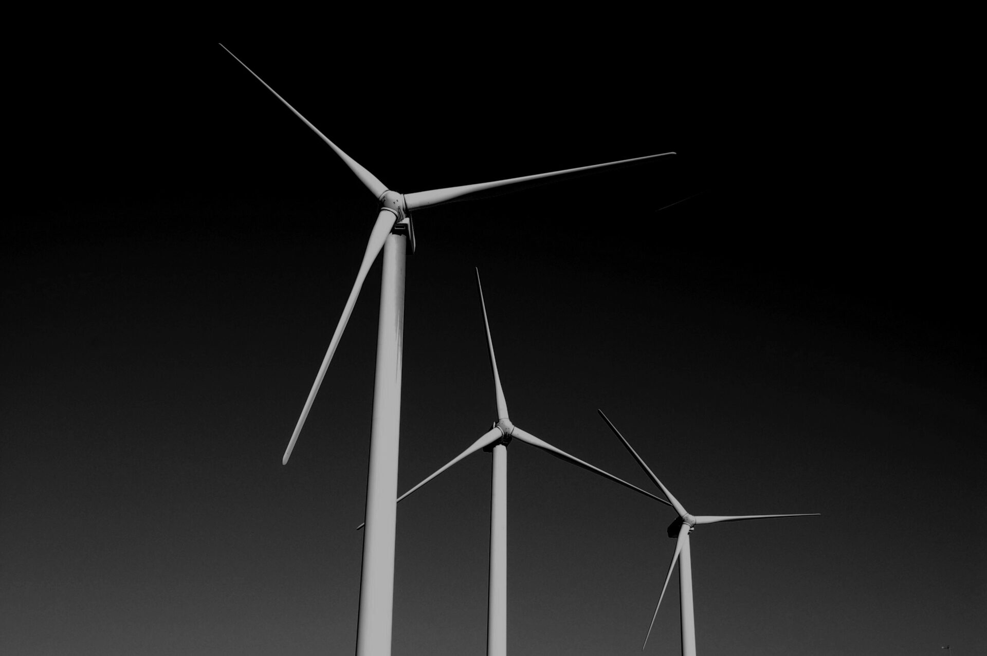 Drei beleuchtete Windräder heben sich vor einem dunklen Hintergrund ab – Symbol für erneuerbare Energie.