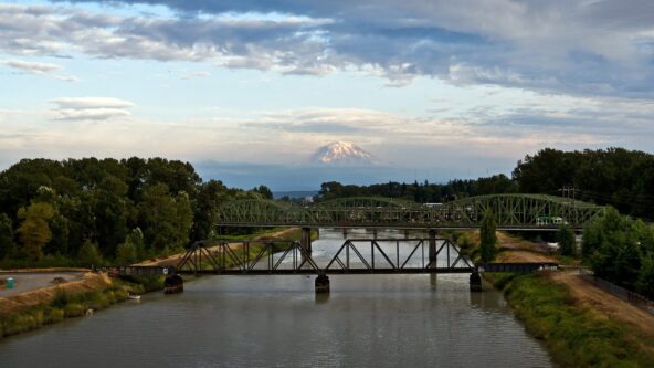 Eine Brücke über einem Fluss mit einem Berg im Hintergrund.