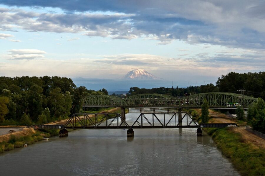 Eine Brücke über einem Fluss mit einem Berg im Hintergrund.