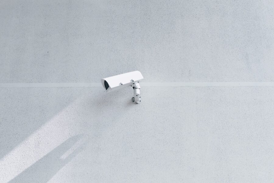 White security camera mounted on a white wall.