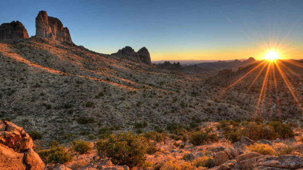 Die Sonne steigt über den Bergen in der Wüste auf.