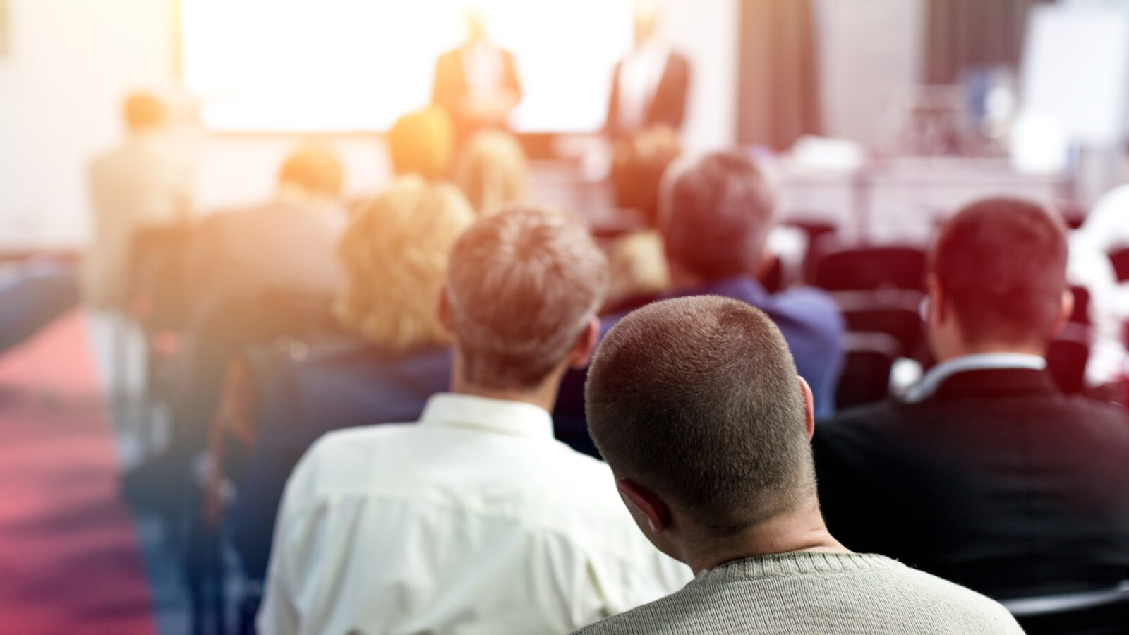Ein Vortrag in einem Sitzungssaal mit vielen Zuhörern während einer Konferenz.