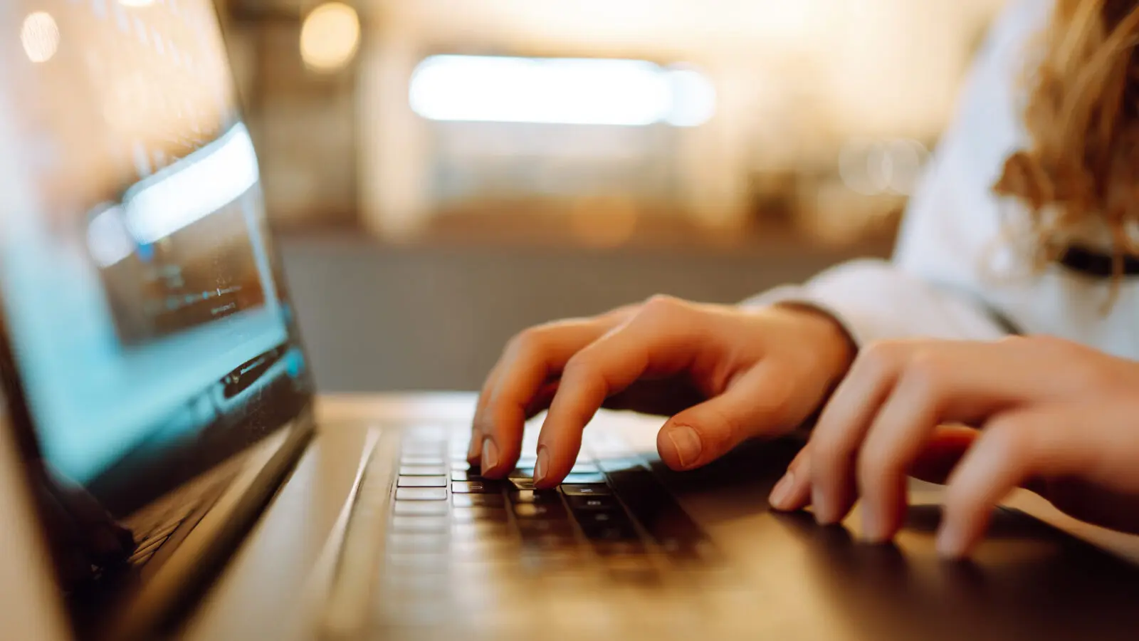 Eine weibliche Hand tippt auf der Tastatur eines Laptops.