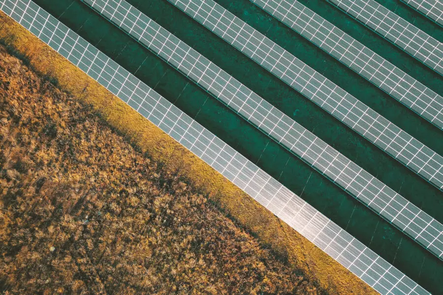 Luftaufnahme eines Solarparks inmitten einer Industrielandschaft, der saubere und erneuerbare Sonnenenergie erzeugt