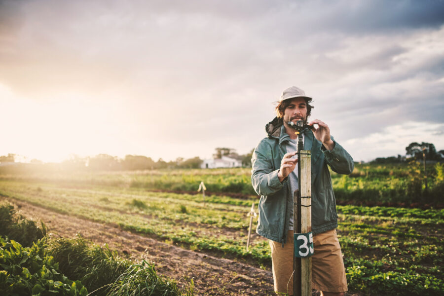 Young man operating an irrigation system in a field to ensure crop irrigation.