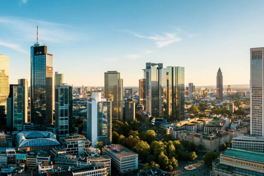 Moderne Stadt mit zahlreichen Wolkenkratzern und Hochhäusern unter einem hellblauen Himmel.