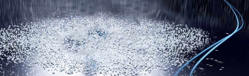 Hailstones and rain falling on a dark, wet surface at night, with blue streaks of light winding through the scene.