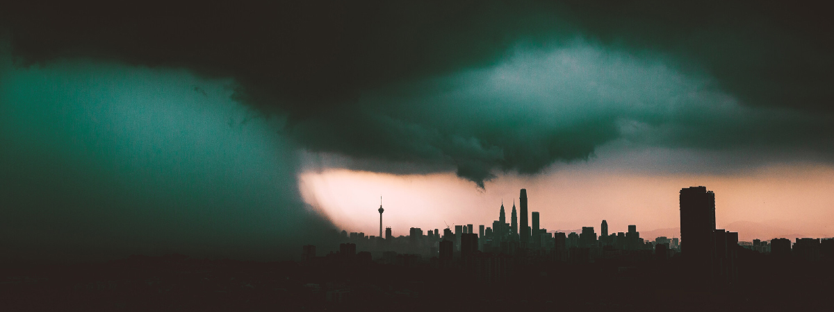 Dark storm clouds are over the skyline of a city at sunset.
