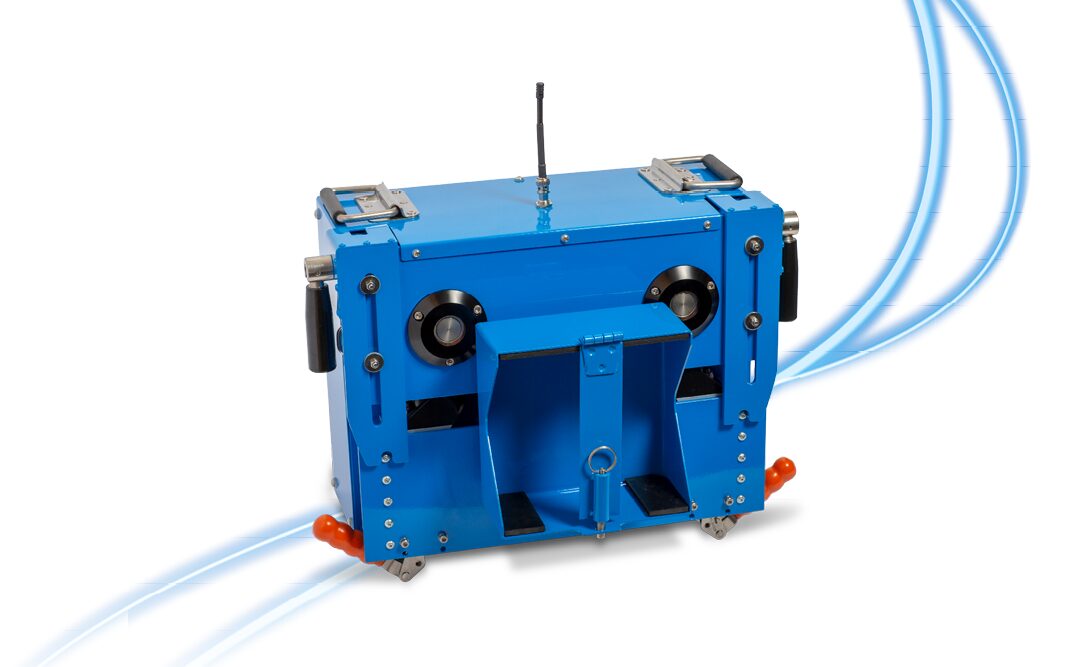 Eine blaue, kastenförmige Industriemaschine mit Griffen, Rädern und einer Antenne vor einem weißen Hintergrund mit hellblauen geschwungenen Linien.