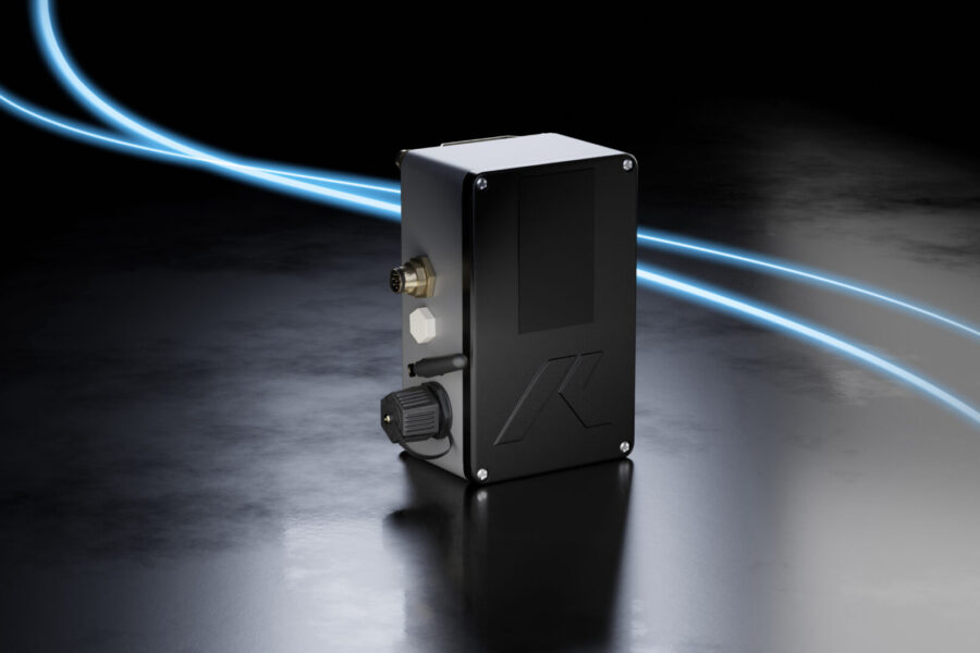 Ein rechteckiges elektronisches Gerät mit verschiedenen Anschlüssen und Steckern steht auf einer dunklen Oberfläche, Lichtspuren sind im Hintergrund.